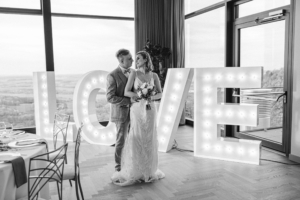 Brautpaar vor leuchtenden LOVE Buchstaben im Panoramahotel